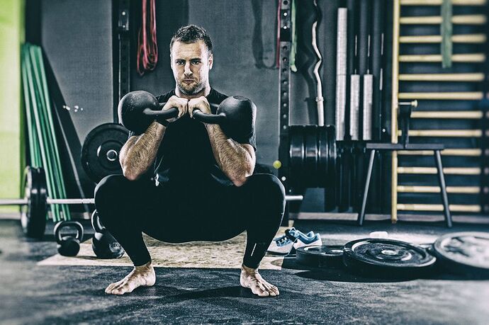 young-man-holding-kettlebell-while-exercising-at-royalty-free-image-1576704910