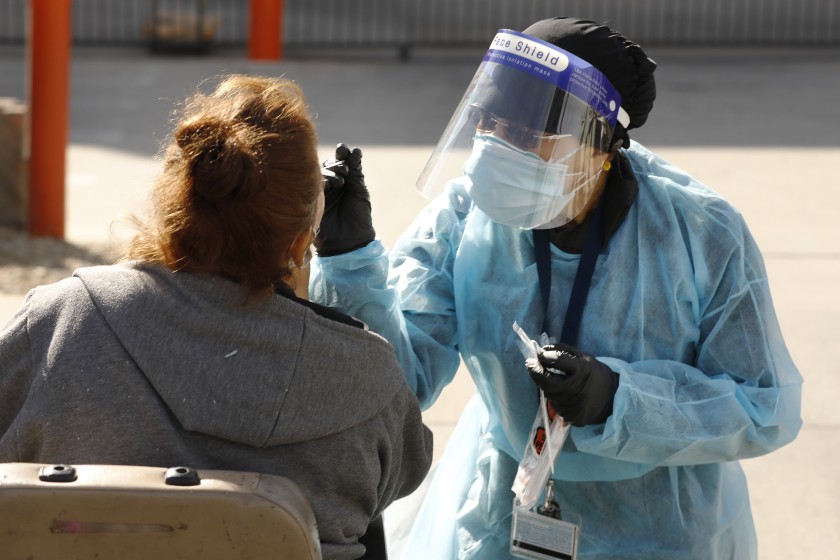 LOS ANGELES, CA - JANUARY 28: Nurse Leah conducts a nasal swab for COVID-19 on a client as outreach workers from various agencies working with the homeless population use a smartphone app called Hot Spots that distributes information about the people they meet. The outreach teams canvas an area on Irwin Ave at West 101st Street in Lennox near LAX. With the Point in Time count canceled this year because of the pandemic, some are suggesting it's time to move on from the massive volunteer to a more data-savvy method using information gathered by outreach workers. Lennox on Thursday, Jan. 28, 2021 in Los Angeles, CA. (Al Seib / Los Angeles Times).