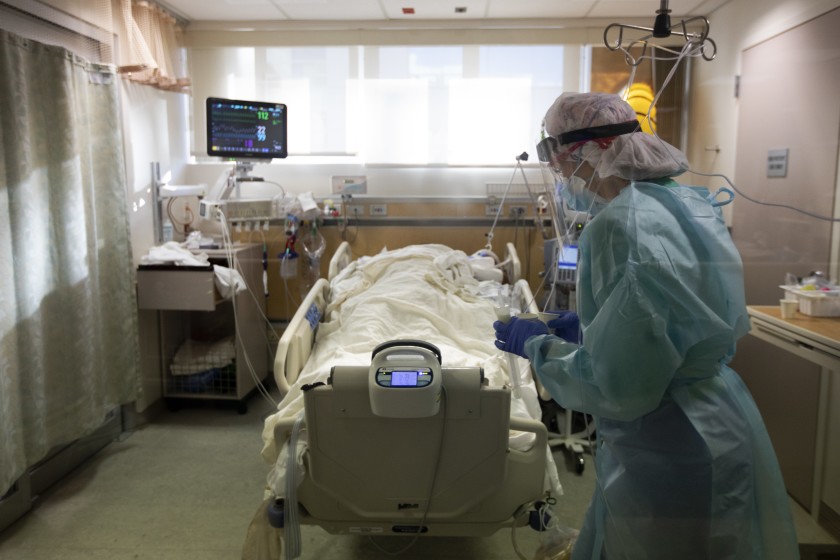 FULLERTON, CA - DECEMBER 25: Bringing in medication Registered Nurse Joan Pung, weaves her way through IV lines in a covid positive patients room inside the ICU at Providence St. Jude Medical Center Christmas Day on Friday, Dec. 25, 2020 in Fullerton, CA. The IV stands have been placed outside the rooms of the covid patients to help the nurses from constantly going into the rooms for their safety from exposure to the virus. The nurses are careful to maneuver through the lines. (Francine Orr / Los Angeles Times)